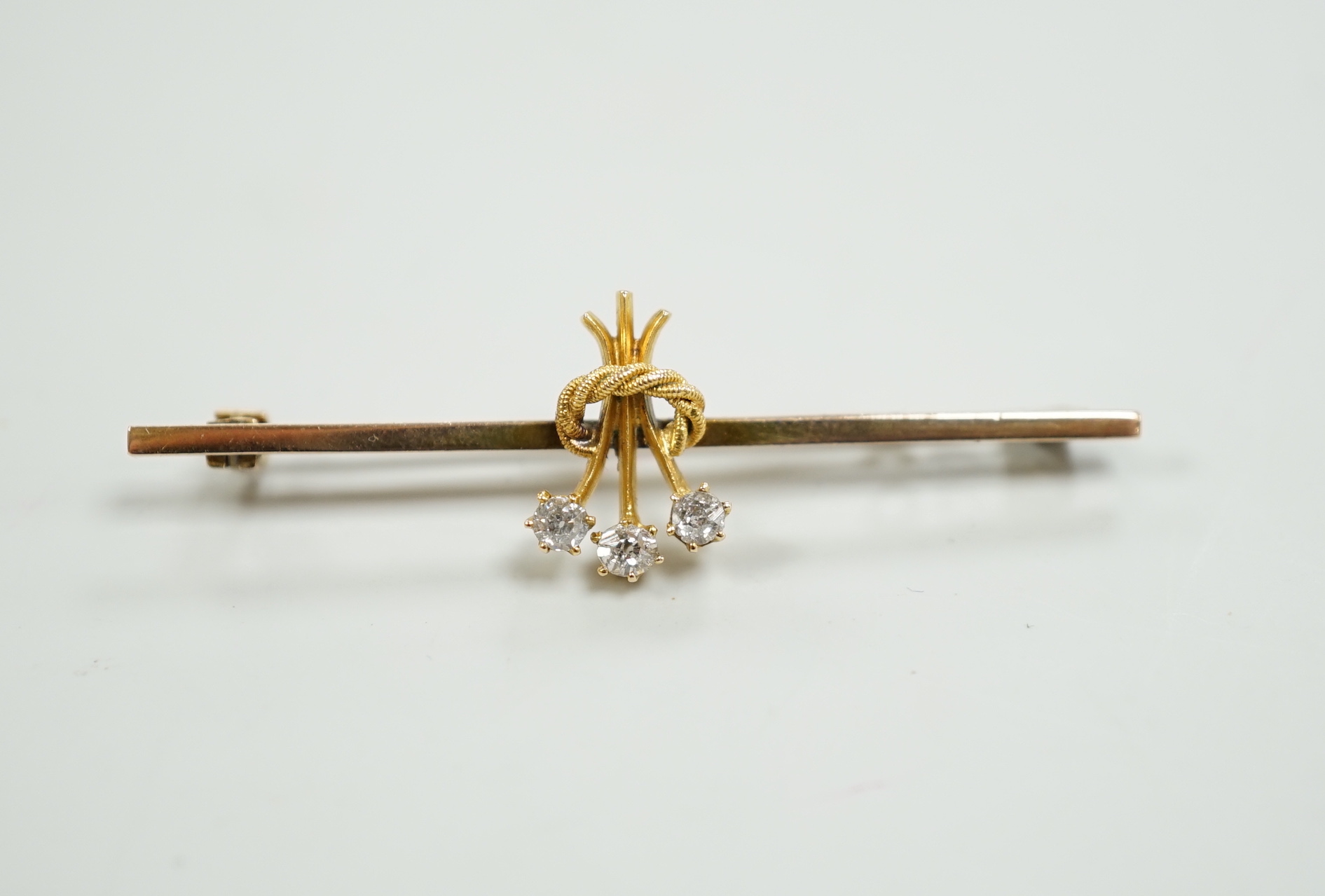 An Edwardian yellow metal and three stone diamond set bar brooch, 46mm, gross weight 2.5 grams.